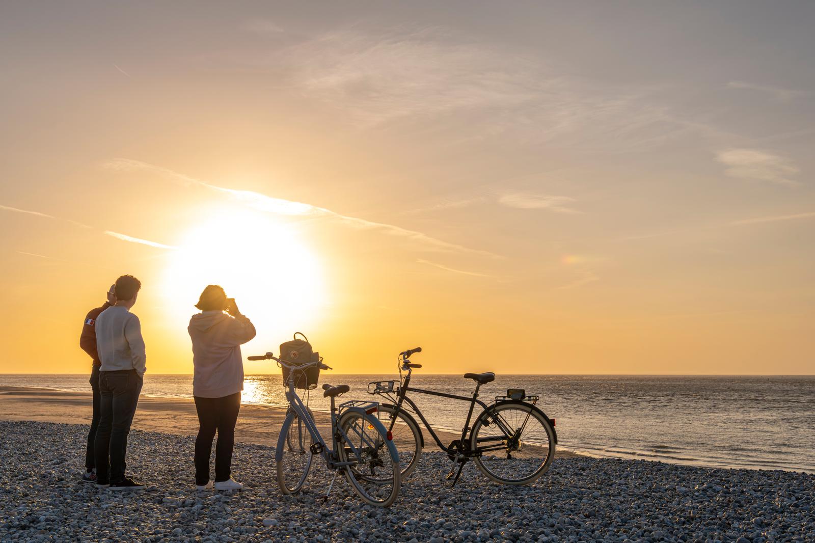 Le Hourdel : cyclistes sur la plage de galets au soleil couchant