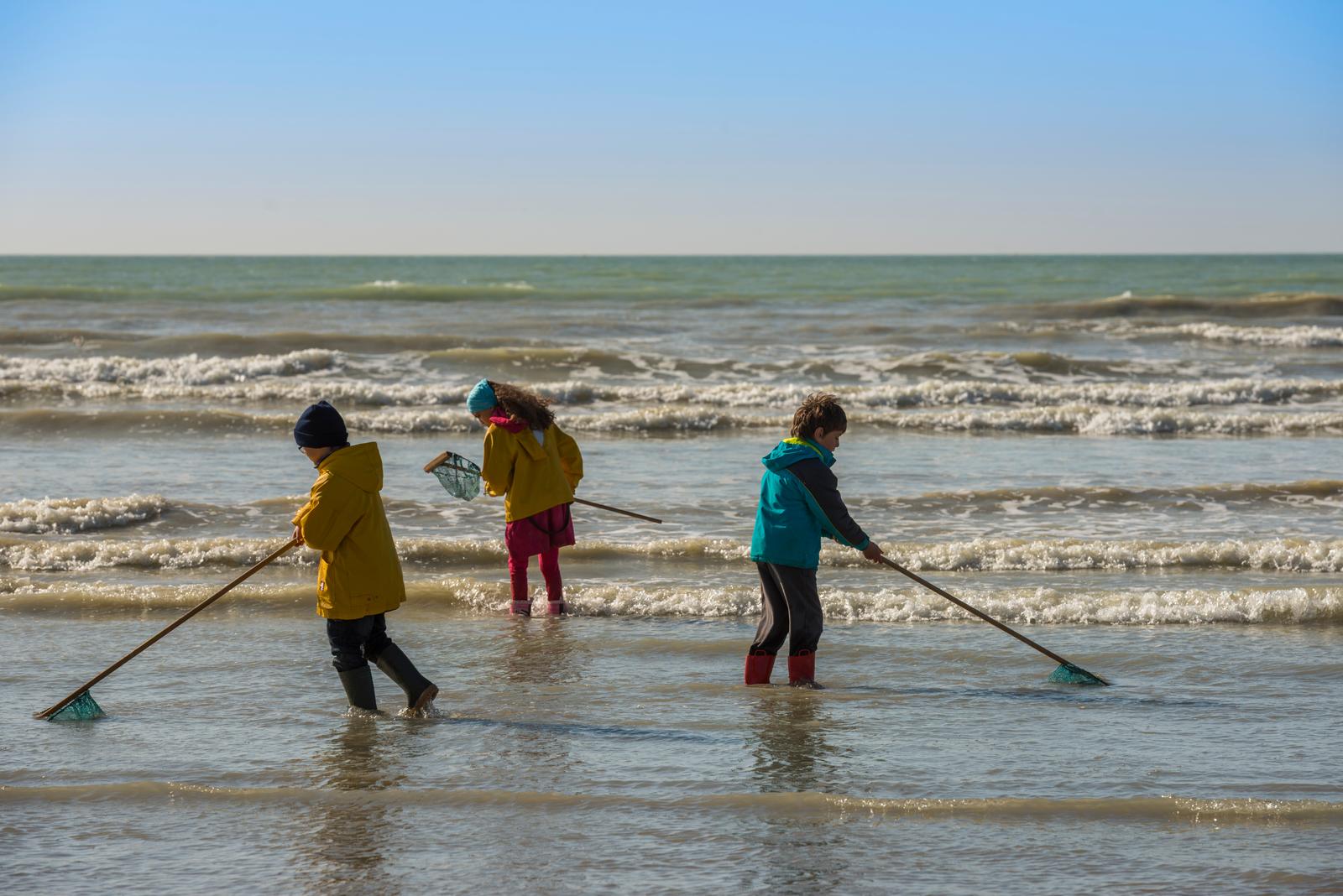 Enfants avec des filets de pêche en bord de mer