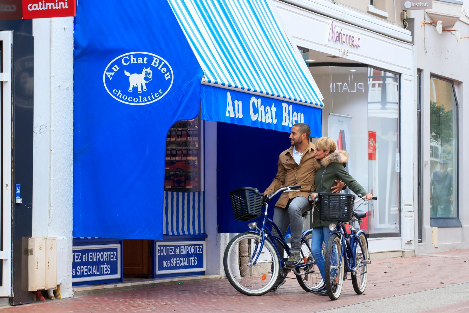 Le Touquet-Paris-Plage : couple à vélo devant le chocolatier Au Chat Bleu